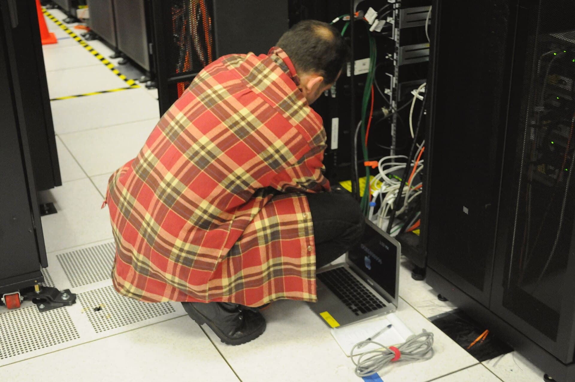 An engineer working directly on a server rack in a data centre